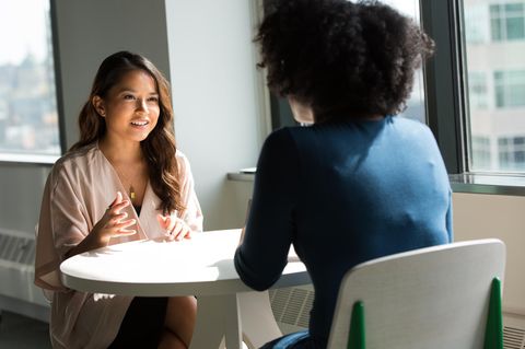 Zwei Frauen sitzen an einem Tisch und unterhalten sich angeregt.
