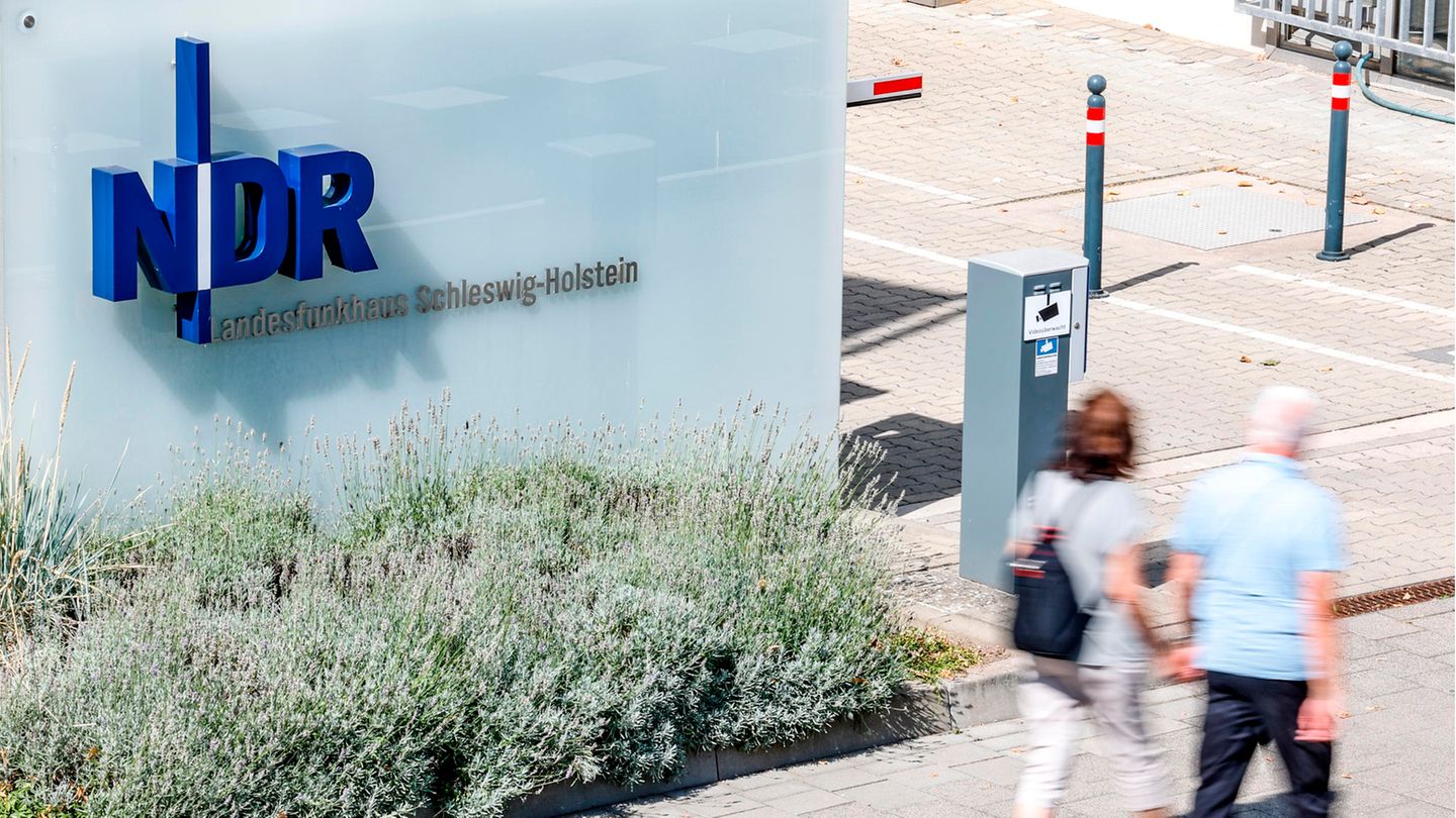 Passanten gehen vor der Einfahrt zum Landesfunkhaus Schleswig-Holstein des NDR entlang