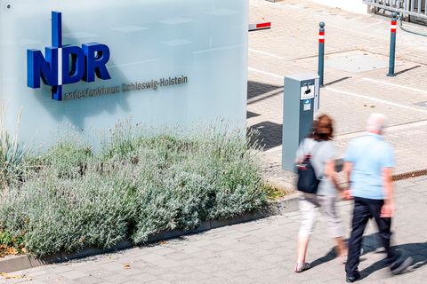 Passanten gehen vor der Einfahrt zum Landesfunkhaus Schleswig-Holstein des NDR entlang