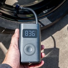 Die Hand, die einen tragbaren Inflator hält, pumpt einen Motorradreifen auf