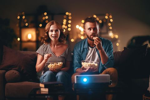 Mann und Frau schauen beim Filmabend auf die Leinwand.