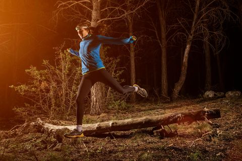 Joggen im Dunkeln: Frau beim Trailrunning im Wald mit Stirnlampe