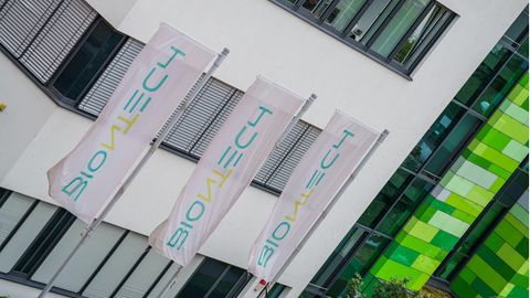 Fahnen mit Biontech-Logo wehen vor dem Hauptsitz des Unternehmens in Mainz