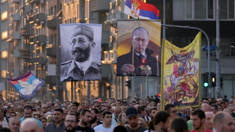 Menschen zeigen Bilder des russischen Präsidenten Putin und Mihailovic während eines Protests