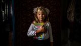 Pokrovske, Ukraine. Die neunjährige Antonia hält ein ukrainisches Schulbuch in den Händen. Das Schulgebäude in dem 24 Seelen großen Ort wurde im russischen Angriffskrieg stark beschädigt. Deshalb nimmt das Mädchen am Online-Unterricht teil.