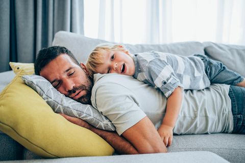 Vater und kleiner Sohn kuscheln auf der Couch