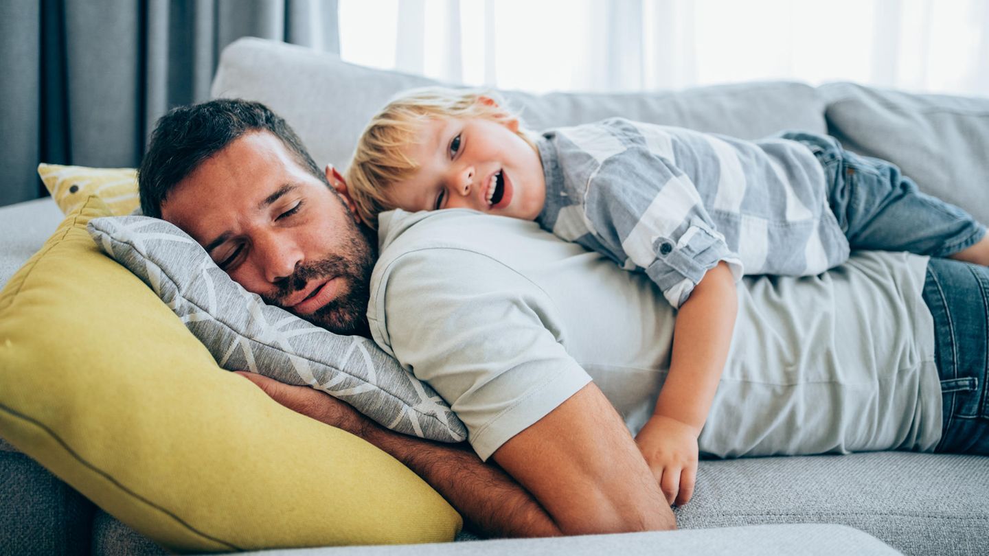Vater und kleiner Sohn kuscheln auf der Couch