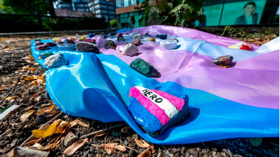 Menschen haben auf dem Hafenplatz in Münster eine Fahne ausgelegt, die mit bemalten Steinen beschwert ist