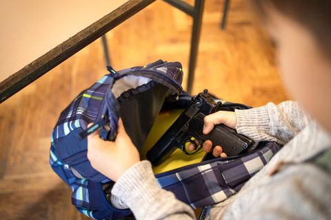 Junge packt Waffe aus seiner Schultasche aus