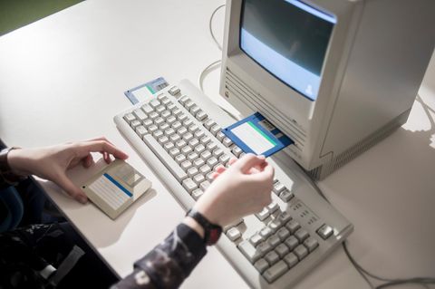 Japan: Ein Frau schiebt eine Diskette in einen alten Computer