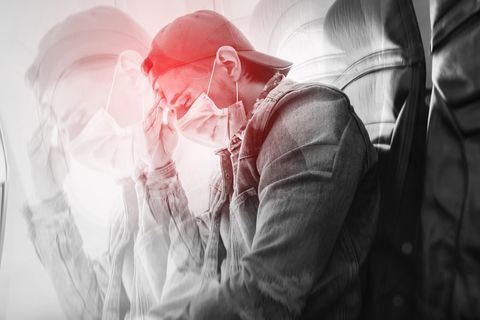Ein Passagier mit geschlossenen Augen und Maske sitzt im Flugzeug