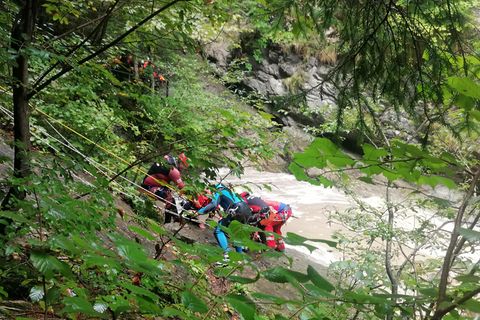 Retter arbeiten in der Starzlachklamm an einem Steilhang am Flussufer.