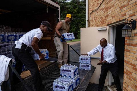 Mitglieder der Progressive Morningstar Baptist Church transportieren Kisten mit Wasser