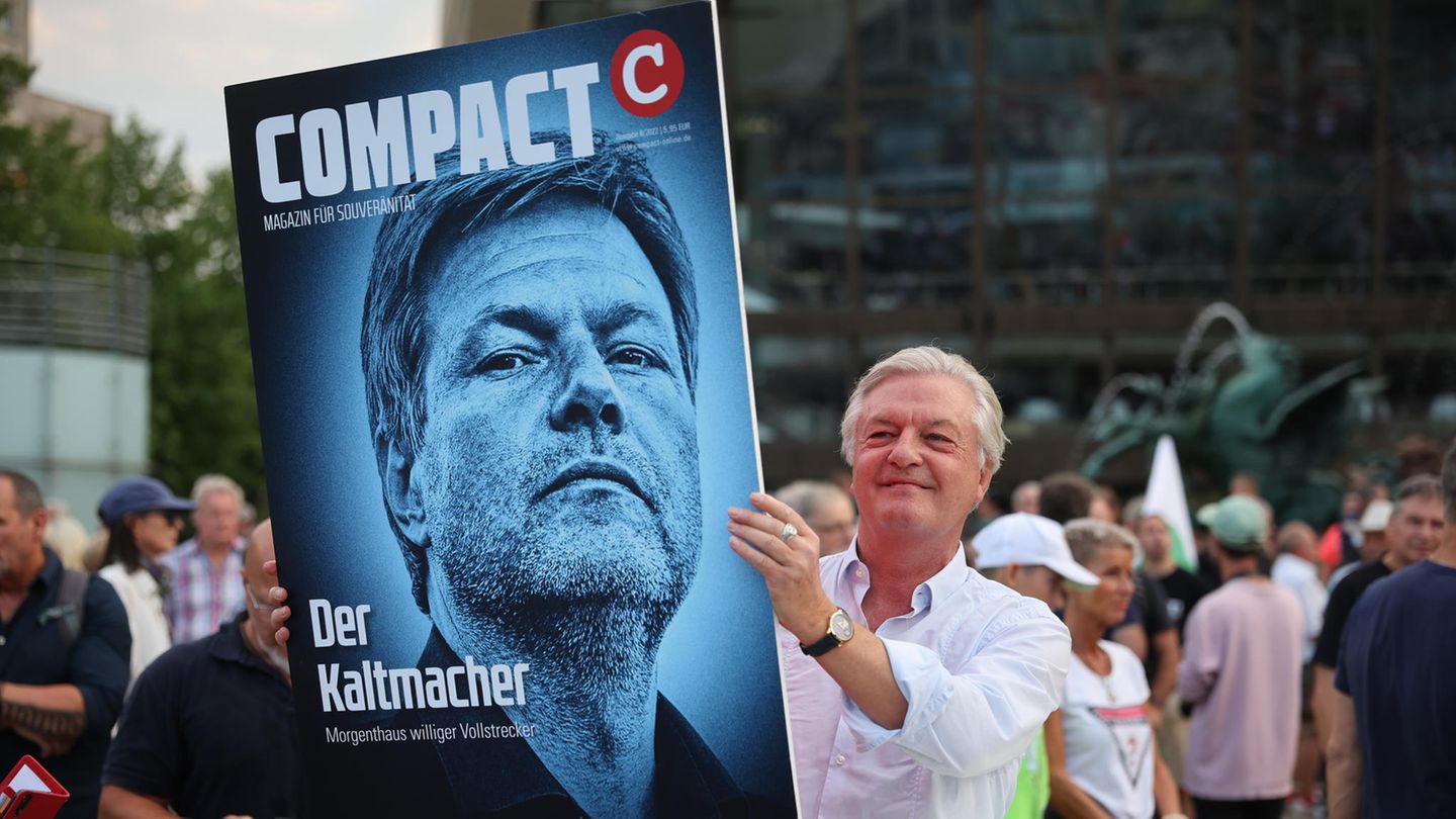 Jürgen Elsässer hält ein Bild mit Habeck in die Höhe