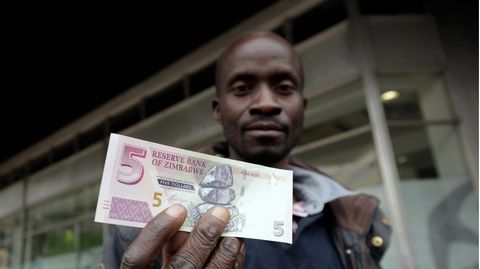 Ein Mann hält eine Fünf-Simbabwe-Dollar-Note in die Kamera