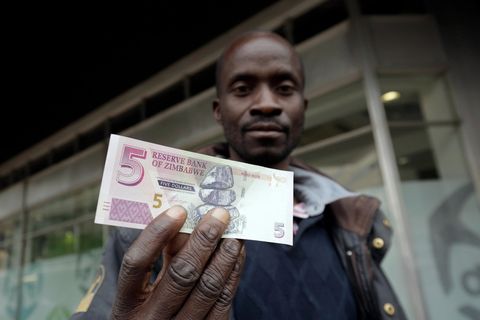 Ein Mann hält eine Fünf-Simbabwe-Dollar-Note in die Kamera