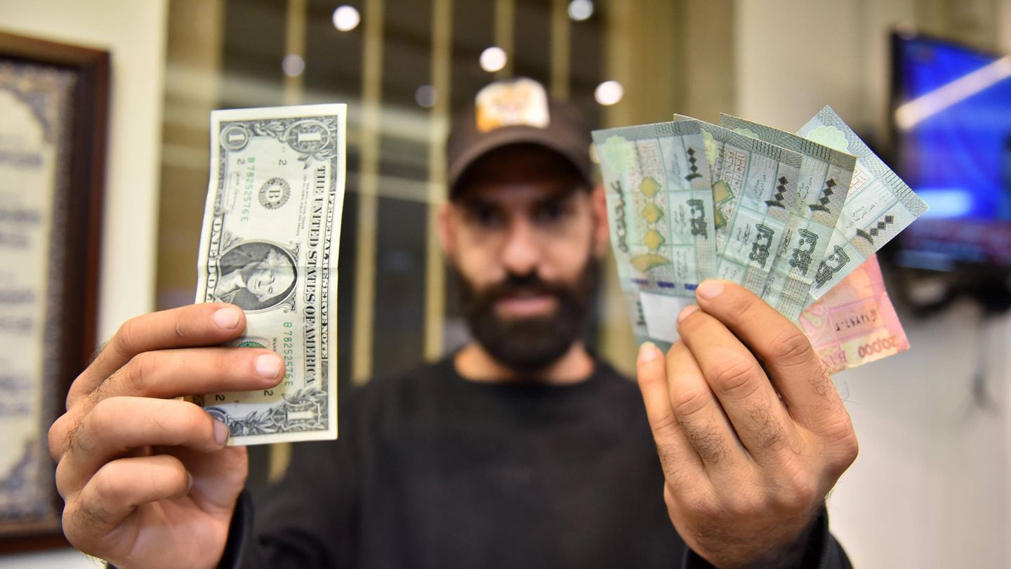 Libanesisches Pfund Ein Mann hält einen US-Dollar-Schein in der einen und mehrere Noten des Libanesischen Pfund in der anderen Hand