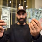 Ein Mann hält einen US-Dollar-Schein in der einen und mehrere Noten des Libanesischen Pfund in der anderen Hand