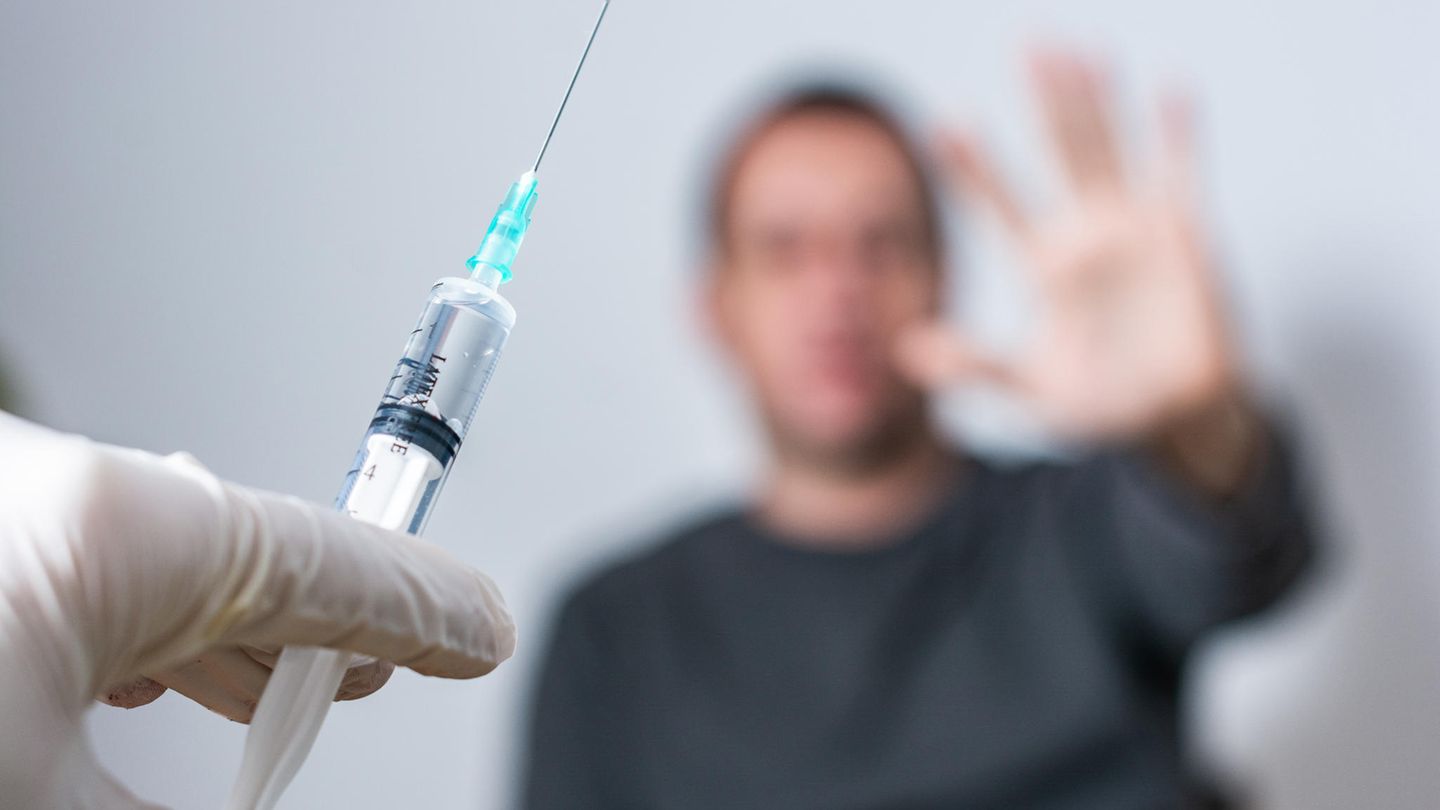 Ein Patient wehrt sich gegen einen Corona-Impfstoff, der in einer Spritze verabreicht werden soll