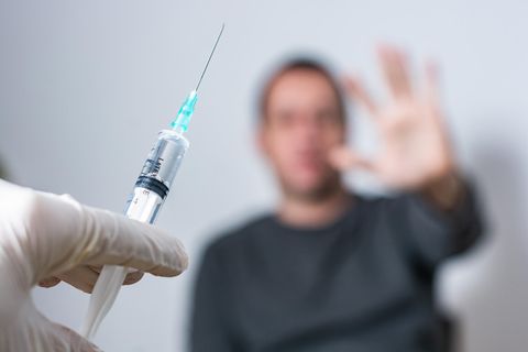 Ein Patient wehrt sich gegen einen Corona-Impfstoff, der in einer Spritze verabreicht werden soll