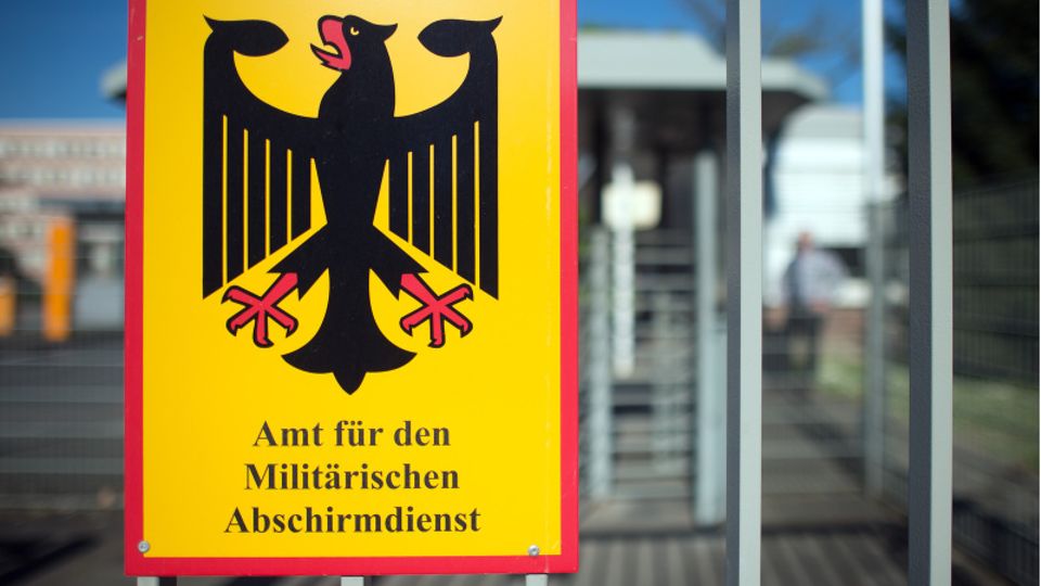 Ein Schild für das Amt für den Militärischen Abschirmdienst (MAD) hängt am Zaun der Konrad-Adenauer-Kaserne in Köln