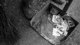 Ein Mann fegt 1946 in Budapest wertlose Pengo-Banknoten zusammen