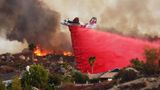 Ein Löschflugzeugen versucht, Häuser an einem Hügel bei Hemet vor den Flammen zu bewahren