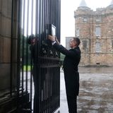 Ein angestellter des Buckingham Palastes hängt die Nachricht über den Tod der Queen an die Tore des Palastes. 