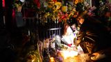 Frau zündet Kerzen an und legt Blumen nieder