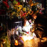 Frau zündet Kerzen an und legt Blumen nieder