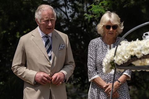 König Charles III. und seine Gemahlin Camilla stehen vor einem Blumenkranz