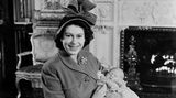 Queen Elizabeth II. sitzt mit ihrem ersten Sohn Prince Charles Philip Arthur George auf einem Stuhl.
