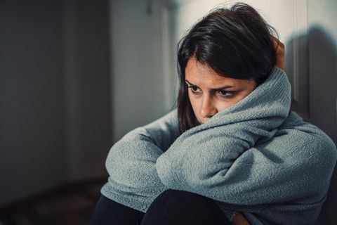Eine Frau sitzt mit verweinten Augen auf dem Boden