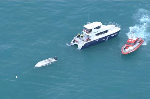 Ein umgedrehtes gekentertes Boot und daneben zwei Rettungsboote