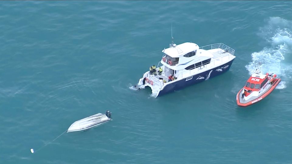 Ein umgedrehtes gekentertes Boot und daneben zwei Rettungsboote
