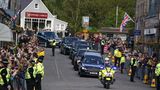 Zuerst geht es durch das knapp 13 Kilometer von Balmoral entfernt liegende Dorf Ballater. Zahlreiche Bewohner stehen am Straßenrand, um ihrer Queen ein letztes Mal Lebewohl zu sagen.