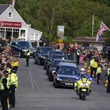 Zuerst geht es durch das knapp 13 Kilometer von Balmoral entfernt liegende Dorf Ballater. Zahlreiche Bewohner stehen am Straßenrand, um ihrer Queen ein letztes Mal Lebewohl zu sagen.