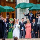 Die Braut steht neben ihren Eltern vor der Kirche