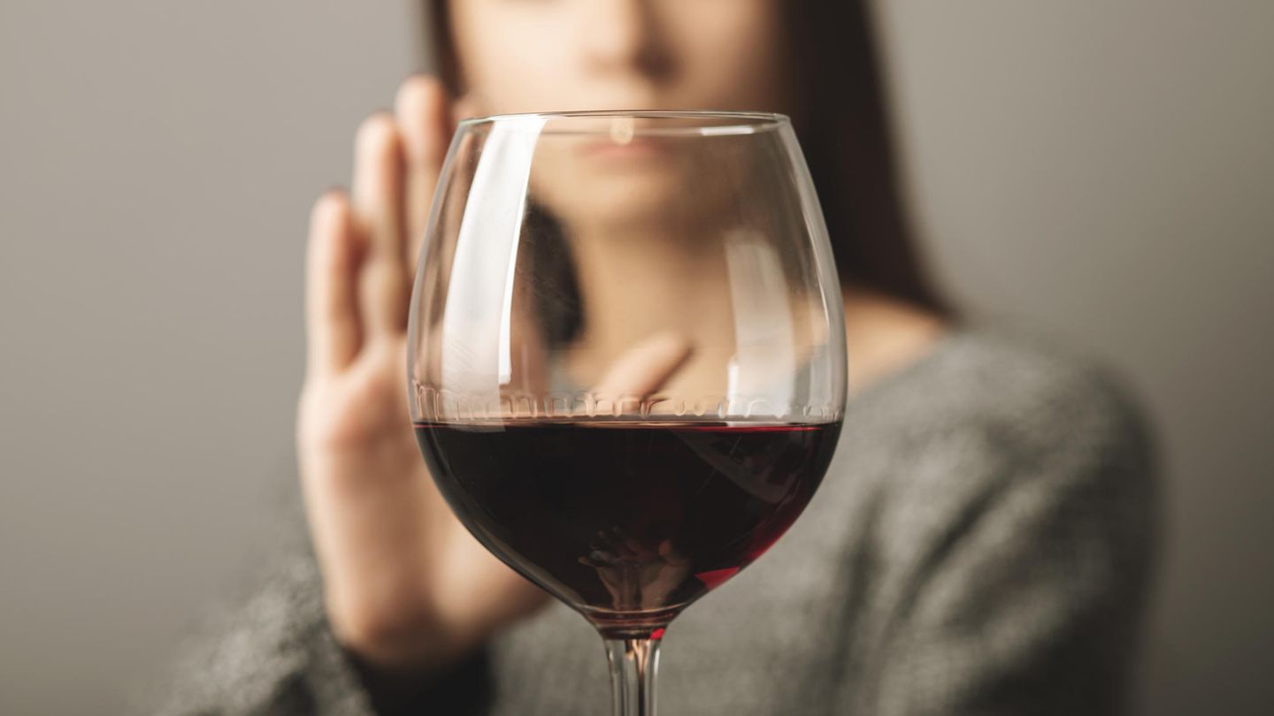 Eine Frau lehnt ein Glas Wein ab.