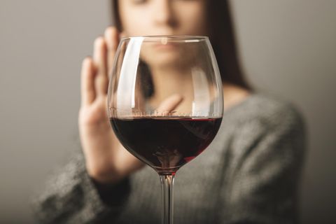 Eine Frau lehnt ein Glas Wein ab.
