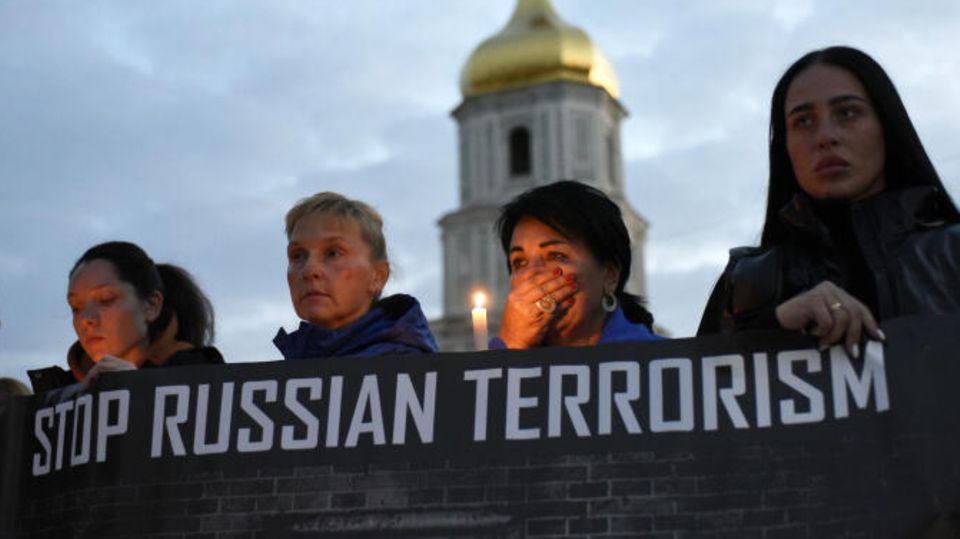 Ukraine: Frauen halten Banner mit der Aufschrift "Stoppt Russlands Terror" hoch
