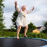 Eine ältere Frau springt glücklich auf einem Trampolin.