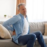 Ein Mann hält sich den schmerzenden Rücken.