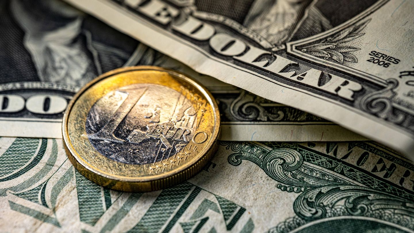 Eine Ein-Euro-Münze liegt auf mehreren Dollar-Scheinen Eine Ein-Euro-Münze liegt auf mehreren Dollar-Scheinen
