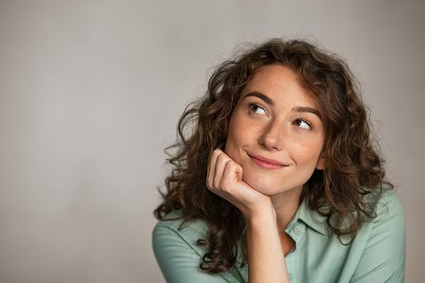 Eine Frau schaut nachdenklich und zufrieden nach oben.