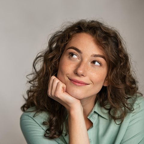Eine Frau schaut nachdenklich und zufrieden nach oben.