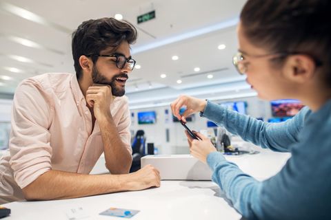 Eine junge Frau erklärt einem Mann ein Apple-Smartphone