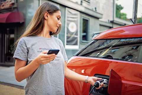 Eine Frau lädt ein Elektroauto auf