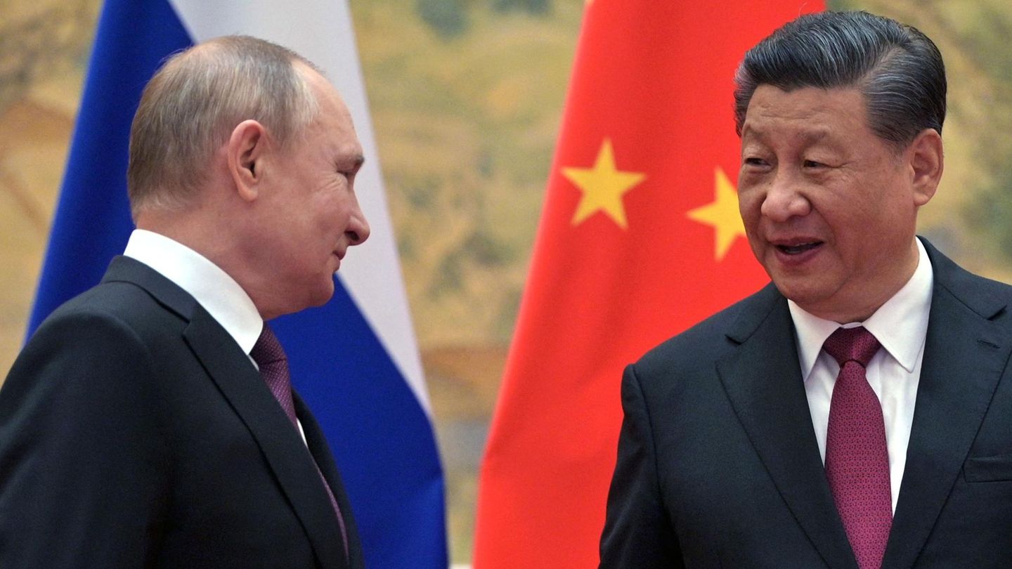Xi Jinping und Putin sprechen vor russischer und chinesischer Flagge miteinander Xi Jinping und Putin sprechen vor russischer und chinesischer Flagge miteinander