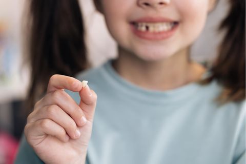 Mädchen hält ausgefallenen Zahn in der Hand